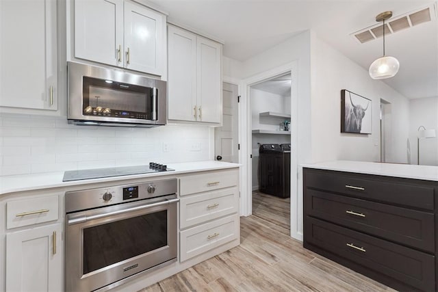 8 Corona Dr, Oklahoma City, OK 73149 - kitchen with appliances with stainless steel finishes, separate washer and dryer, light countertops, and backsplash