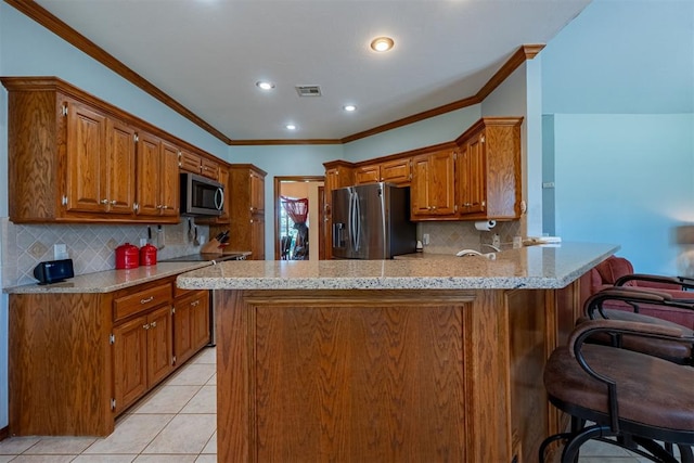 4700 SE 118th St, Oklahoma City, OK 73165 - kitchen with appliances with stainless steel finishes, a peninsula, light tile patterned floors, brown cabinets, and crown molding