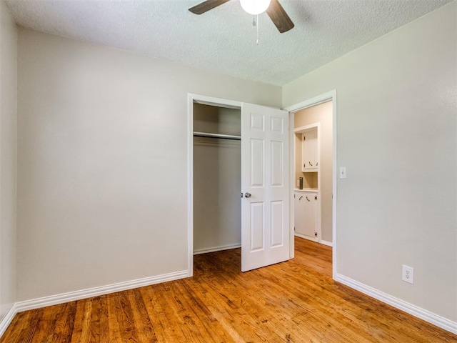 117 Asbill Ave, Yukon, OK 73099 - unfurnished bedroom featuring light wood-style flooring, a textured ceiling, a closet, and ceiling fan
