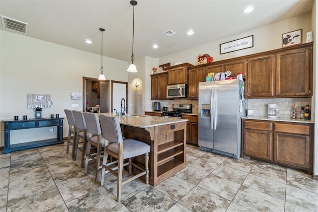 3730 Ruby Rdg, Piedmont, OK 73078 - kitchen featuring appliances with stainless steel finishes, backsplash, an island with sink, a breakfast bar, and pendant lighting