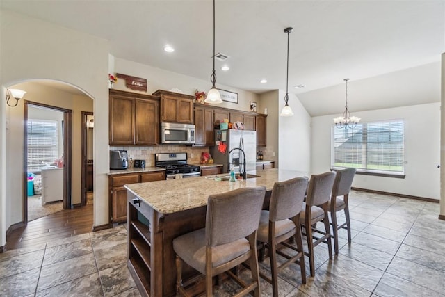 3730 Ruby Rdg, Piedmont, OK 73078 - kitchen with appliances with stainless steel finishes, arched walkways, a kitchen island with sink, backsplash, and open shelves