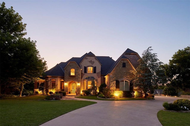 3325 Winding Creek Cir, Edmond, OK 73034 - french country inspired facade featuring stone siding, curved driveway, a lawn, and stucco siding