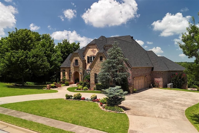 3325 Winding Creek Cir, Edmond, OK 73034 - french country home featuring curved driveway, stone siding, a front lawn, and a garage
