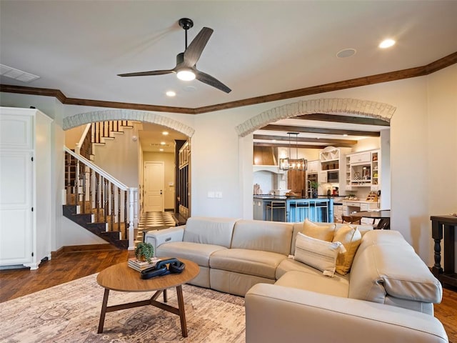 3325 Winding Creek Cir, Edmond, OK 73034 - living room with arched walkways, a ceiling fan, wood finished floors, stairs, and crown molding