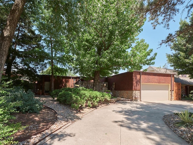7501 Brookside Dr, Oklahoma City, OK 73132 - view of front of house with stone siding, an attached garage, and driveway
