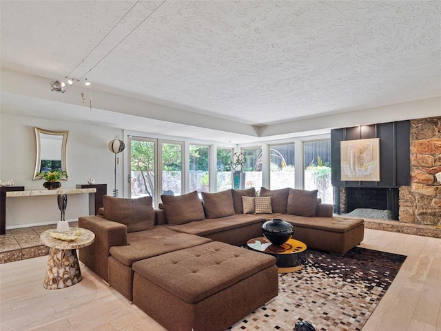 7501 Brookside Dr, Oklahoma City, OK 73132 - living room with a textured ceiling, hardwood / wood-style floors, and a stone fireplace