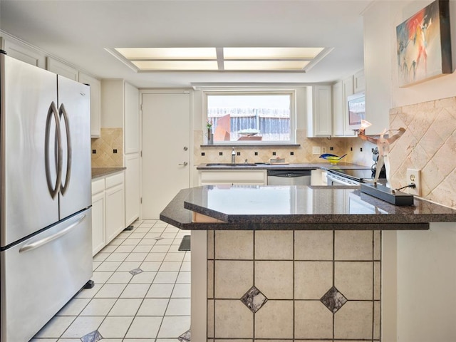 7501 Brookside Dr, Oklahoma City, OK 73132 - kitchen featuring freestanding refrigerator, stainless steel dishwasher, tasteful backsplash, a peninsula, and white microwave