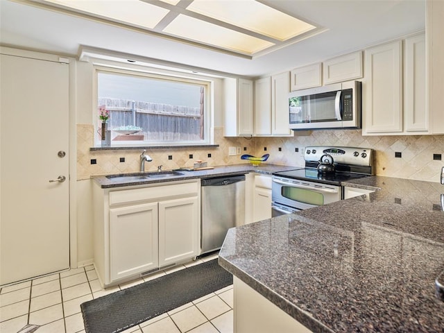 7501 Brookside Dr, Oklahoma City, OK 73132 - kitchen featuring appliances with stainless steel finishes, light tile patterned floors, decorative backsplash, dark stone counters, and white cabinets