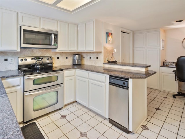 7501 Brookside Dr, Oklahoma City, OK 73132 - kitchen with appliances with stainless steel finishes, light tile patterned flooring, white cabinetry, and decorative backsplash