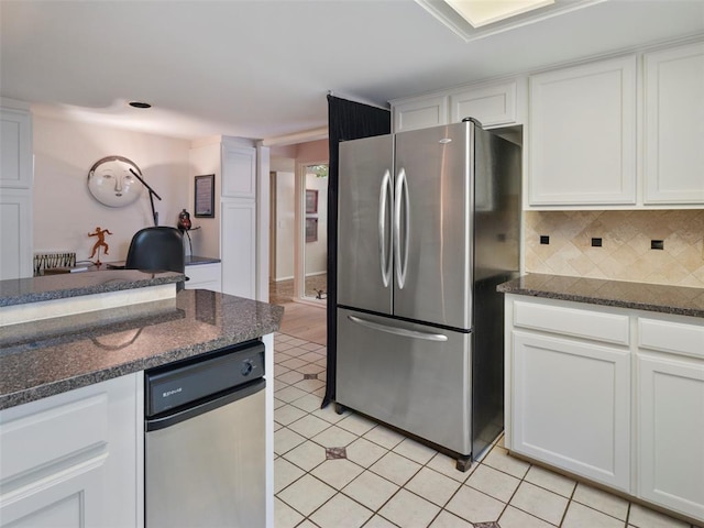 7501 Brookside Dr, Oklahoma City, OK 73132 - kitchen featuring freestanding refrigerator, white cabinetry, light tile patterned floors, decorative backsplash, and dark stone counters