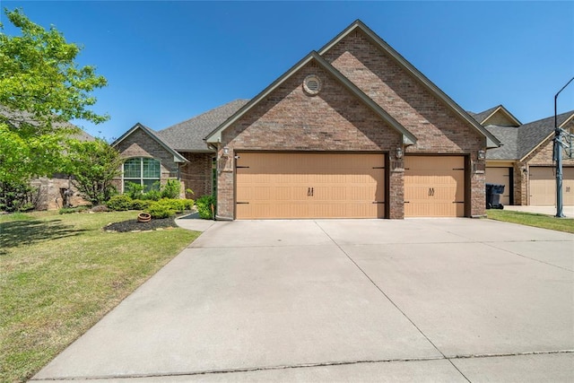 2828 Ryder Dr, Yukon, OK 73099 - view of front of home featuring an attached garage, driveway, a front yard, and brick siding