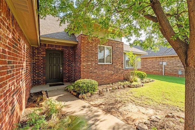 2429 NW 176th St, Edmond, OK 73012 - doorway to property featuring a shingled roof, brick siding, and a lawn