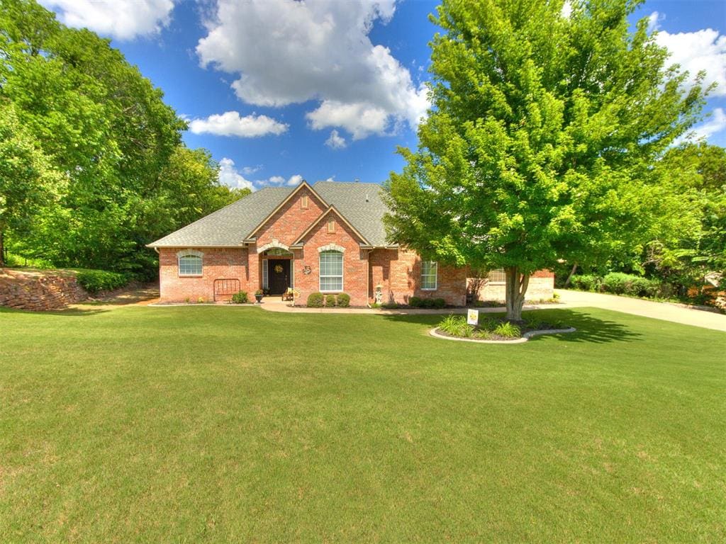 1821 Oak Creek Ter, Edmond, OK 73034 - ranch-style home featuring brick siding, a front yard, and a shingled roof