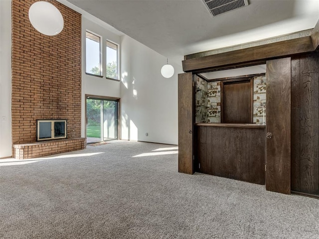 9220 Sutton Pl, Oklahoma City, OK 73132 - unfurnished living room with carpet flooring, a brick fireplace, healthy amount of natural light, and a towering ceiling