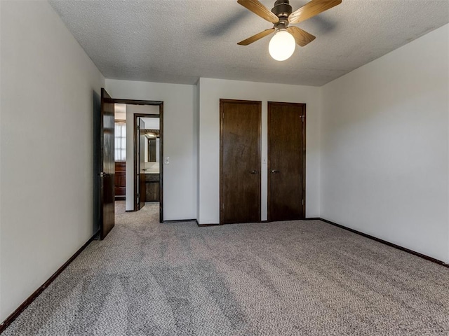 9220 Sutton Pl, Oklahoma City, OK 73132 - unfurnished bedroom with two closets, light colored carpet, a textured ceiling, and ceiling fan