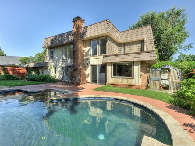 9220 Sutton Pl, Oklahoma City, OK 73132 - back of property featuring an outdoor pool, a chimney, a patio, brick siding, and mansard roof