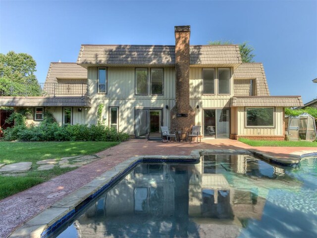 9220 Sutton Pl, Oklahoma City, OK 73132 - back of property with mansard roof, a patio area, board and batten siding, and an outdoor pool