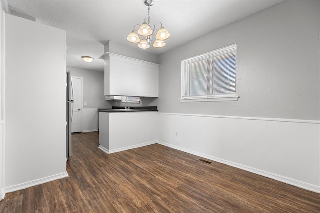 4101 NW 51st St, Oklahoma City, OK 73112 - kitchen with white cabinetry, dark wood-style floors, dark countertops, a chandelier, and pendant lighting