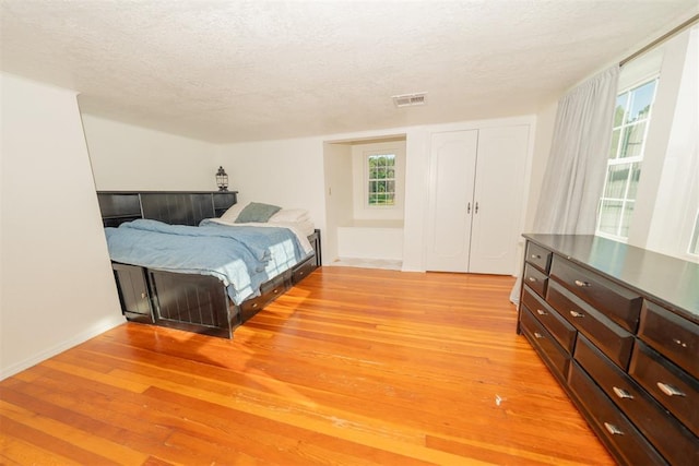 1301 E Rock Creek Rd, Tuttle, OK 73089 - bedroom featuring light wood-type flooring, a textured ceiling, and multiple windows