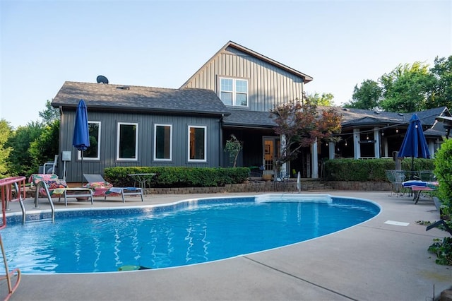 1301 E Rock Creek Rd, Tuttle, OK 73089 - rear view of property featuring an outdoor pool, a patio, board and batten siding, and a shingled roof