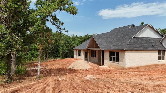 8121 Red Feather, Arcadia, OK 73007 - view of front of house featuring a shingled roof, board and batten siding, and brick siding