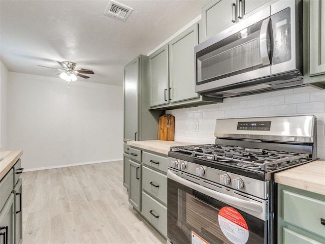 2753 SW 46th Pl, Oklahoma City, OK 73119 - kitchen with stainless steel appliances, a ceiling fan, green cabinetry, light wood finished floors, and backsplash