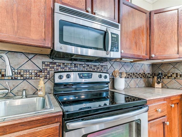 1122 NW 42nd St, Oklahoma City, OK 73118 - kitchen with stainless steel appliances, decorative backsplash, light countertops, and brown cabinetry