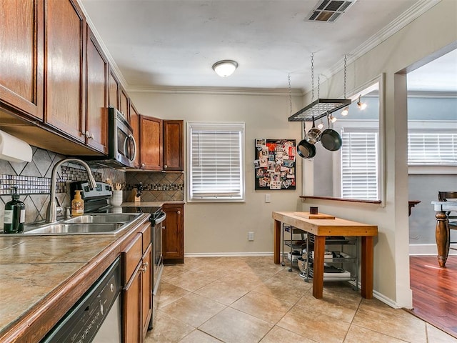 1122 NW 42nd St, Oklahoma City, OK 73118 - kitchen featuring appliances with stainless steel finishes, tasteful backsplash, ornamental molding, light tile patterned floors, and healthy amount of natural light