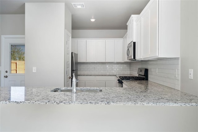 9300 NW 126th St, Yukon, OK 73099 - kitchen with stainless steel appliances, light stone counters, tasteful backsplash, and white cabinets