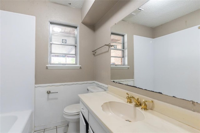 1512 SW 77th Ter, Oklahoma City, OK 73159 - bathroom with vanity, a textured ceiling, healthy amount of natural light, a bath, and a wainscoted wall