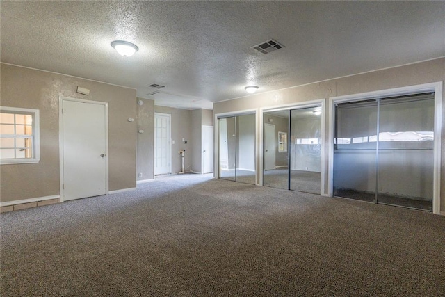 1512 SW 77th Ter, Oklahoma City, OK 73159 - unfurnished bedroom featuring a textured ceiling, two closets, carpet flooring, and multiple windows