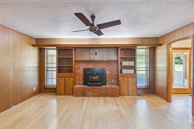 13722 NE 9th St, Choctaw, OK 73020 - unfurnished living room featuring wood finished floors, wooden walls, a textured ceiling, a ceiling fan, and a wood stove