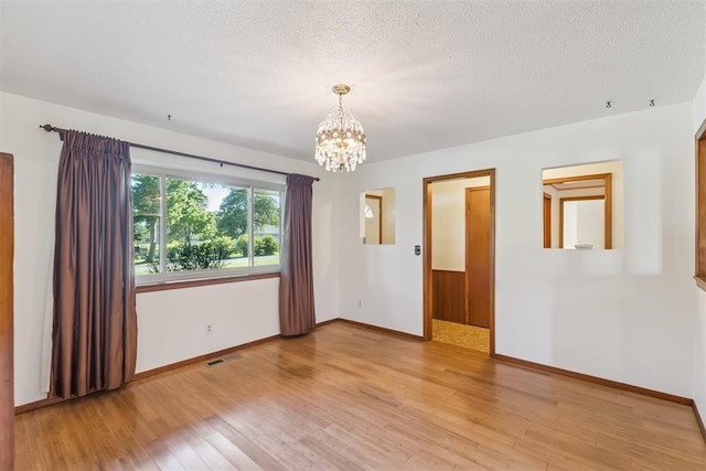 13722 NE 9th St, Choctaw, OK 73020 - spare room with a chandelier, light wood-style floors, and a textured ceiling