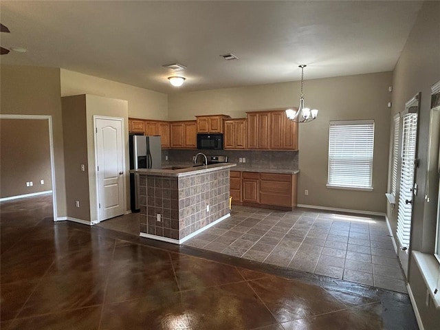 1108 SW 158th St, Oklahoma City, OK 73170 - kitchen featuring black microwave, stainless steel fridge, a center island with sink, tasteful backsplash, and a chandelier