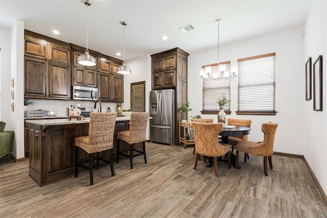 13 Ivory Dr, Yukon, OK 73099 - kitchen with stainless steel appliances, wood finished floors, dark brown cabinetry, a chandelier, and tasteful backsplash
