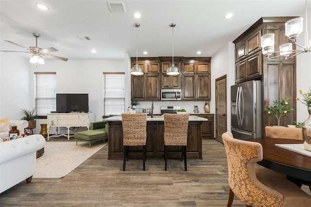 13 Ivory Dr, Yukon, OK 73099 - kitchen featuring stainless steel appliances, open floor plan, dark brown cabinets, dark wood-type flooring, and a breakfast bar