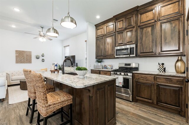 13 Ivory Dr, Yukon, OK 73099 - kitchen featuring stainless steel appliances, a ceiling fan, dark wood-style floors, a breakfast bar area, and recessed lighting