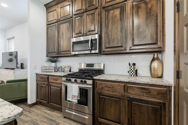 13 Ivory Dr, Yukon, OK 73099 - kitchen featuring stainless steel appliances, backsplash, wood finished floors, dark brown cabinets, and light stone counters
