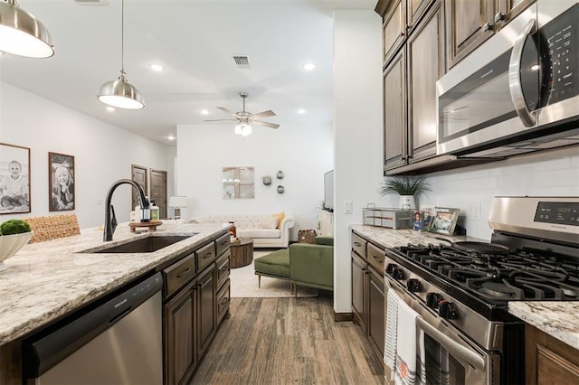 13 Ivory Dr, Yukon, OK 73099 - kitchen featuring appliances with stainless steel finishes, backsplash, light stone counters, dark wood-type flooring, and a ceiling fan