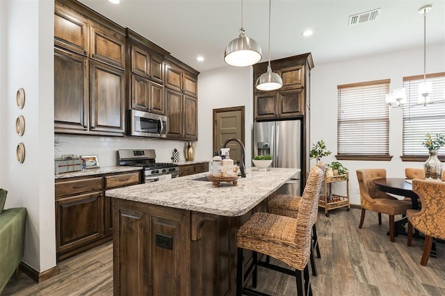 13 Ivory Dr, Yukon, OK 73099 - kitchen featuring appliances with stainless steel finishes, dark brown cabinetry, a kitchen breakfast bar, dark wood finished floors, and recessed lighting