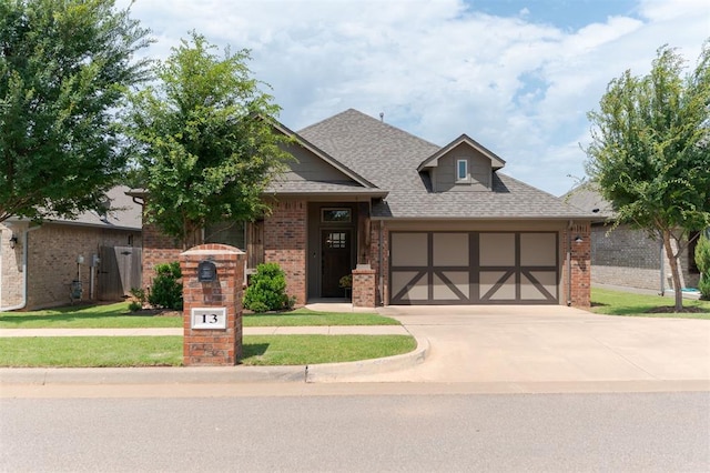 13 Ivory Dr, Yukon, OK 73099 - view of front of house with brick siding, an attached garage, driveway, and a shingled roof