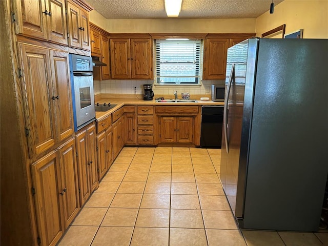 5612 NW 65th St, Warr Acres, OK 73132 - kitchen with black appliances, a textured ceiling, decorative backsplash, and brown cabinets