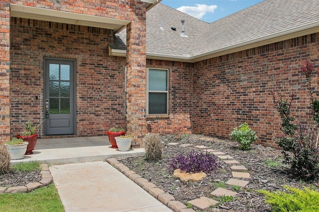 12825 SW 26th St, Yukon, OK 73099 - view of exterior entry featuring roof with shingles and brick siding