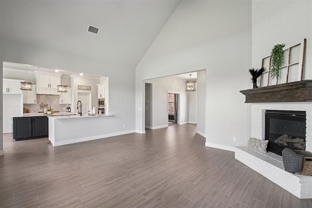 12825 SW 26th St, Yukon, OK 73099 - unfurnished living room with high vaulted ceiling, dark wood finished floors, a fireplace, and a chandelier