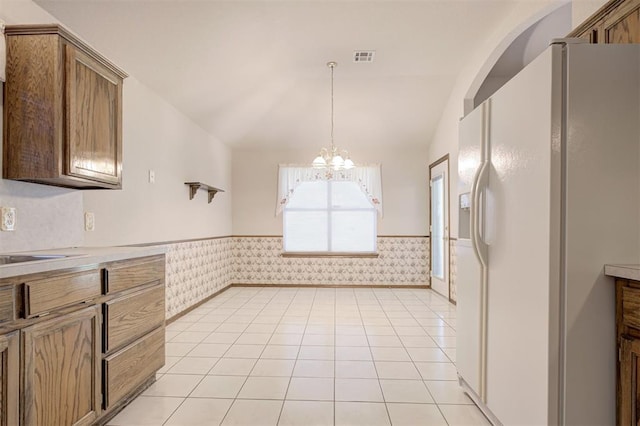 2401 Westchester Dr, Moore, OK 73160 - kitchen with white fridge with ice dispenser, a wainscoted wall, a chandelier, vaulted ceiling, and decorative light fixtures