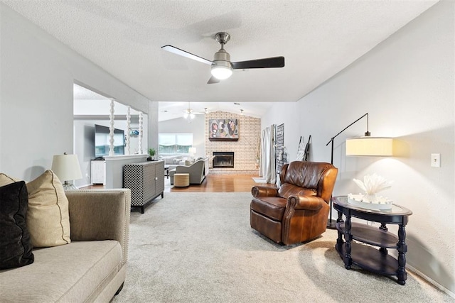 815 W 7th St, Edmond, OK 73003 - carpeted living room with ceiling fan, vaulted ceiling, a fireplace, and a textured ceiling