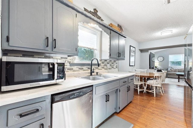 815 W 7th St, Edmond, OK 73003 - kitchen featuring stainless steel appliances, gray cabinetry, tasteful backsplash, light wood-style flooring, and light countertops