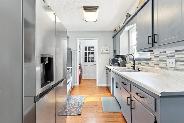 815 W 7th St, Edmond, OK 73003 - kitchen with stainless steel appliances, decorative backsplash, washer / clothes dryer, light wood-style flooring, and light countertops