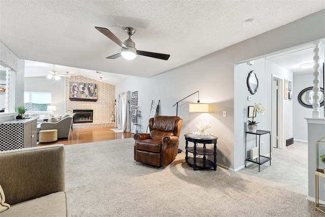 815 W 7th St, Edmond, OK 73003 - living room featuring a ceiling fan, a fireplace, vaulted ceiling, carpet flooring, and a textured ceiling