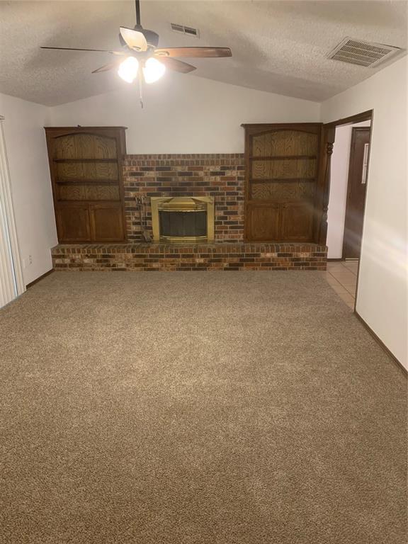 515 Cripple Creek Dr, Norman, OK 73071 - unfurnished living room featuring a textured ceiling, a ceiling fan, a fireplace, carpet flooring, and lofted ceiling
